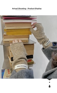 Knitted oat fingerless gloves featuring a nice moment patch shown in a cozy library setting