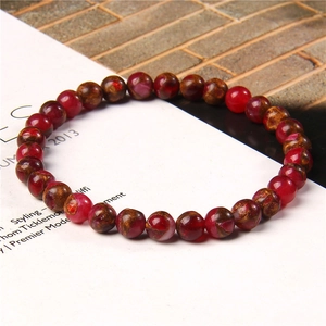 Macro shot of 6mm red agate beads with golden glitter textures on a white magazine