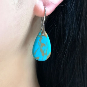 Detail of bohemian teardrop turquoise earring with vintage silver hook on model