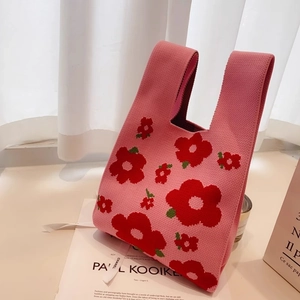 Detail shot of a pink floral knitted tote bag with textured red flower patterns