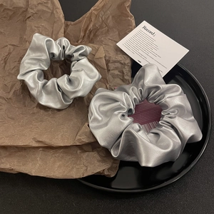 Detailed view of silver metallic PU leather scrunchies with pleated texture on props
