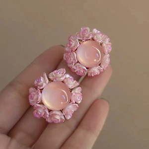 Close-up of pink rose flower earrings with shiny cat eye stone and delicate resin petals