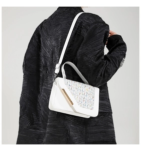 Détail du sac bandoulière en tweed blanc avec barre métallique et lanière en cuir