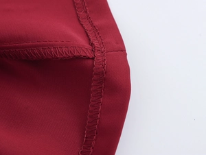 Detaillierte Nahaufnahme der hochwertigen Nähte auf dunkelrotem Tweed-Stoffkleid