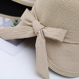 Detailed macro view of woven straw sun hat featuring a textured bow and black trim