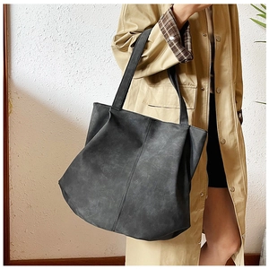 Close-up of black retro tote bag with textured faux leather and vertical stitching