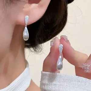 Brushed silver waterdrop earrings with pavé zircon detail on a female model
