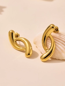 Detailed view of teardrop two-tone stud earrings on a shell in 18K gold stainless steel