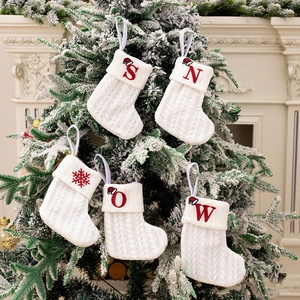 Set of 4 white knitted Christmas stockings with red SNOW embroidery on a festive tree