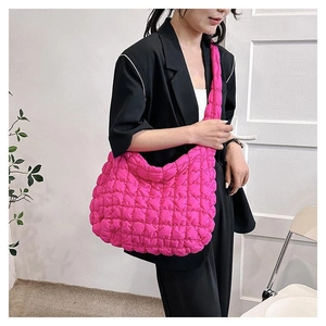 Detailed view of hot pink quilted cloud bag featuring soft pleated texture and wide strap