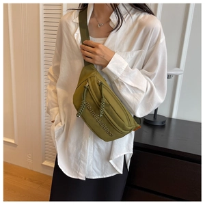 Detail of green nylon chest bag with embroidered letters and adjustable strap
