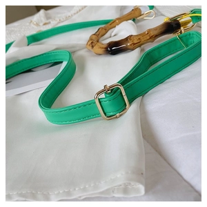 Detail of green faux leather strap and bamboo handle with gold-tone hardware for women handbag