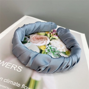 Macro detail of blue pleated satin headband with silky texture on vintage magazine