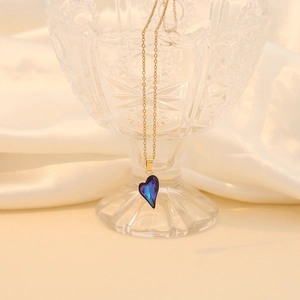 Detailed view of a purple glass heart pendant with a gold chain on white silk background