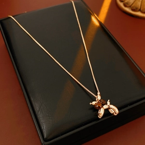 Close-up of a gold-plated puppy pendant necklace on a premium black leather display pad