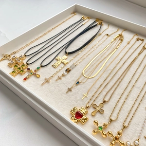 Detailed display of assorted gold cross necklaces and gemstone pendants on a white jewelry tray