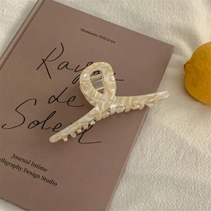 Detail view of large marble texture hair claw clip resting on a vintage book