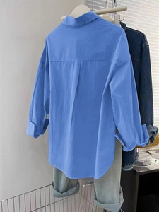 Vue arrière d'une chemise ample en lin bleu à manches longues suspendue à un cintre