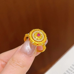 Détail d'une bague dorée vintage avec pierre rouge, zircone et gravure en émail