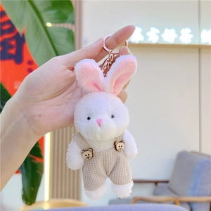 Detalle de llavero de conejo de peluche con peto a rayas y botones de osito