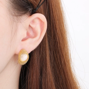 Close-up of vintage gold earrings with cream opal stones and textured metal grain