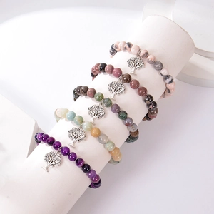 Detail view of tree of life charm bracelets with natural stone beads on a display stand