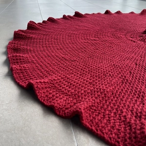 Macro shot of red chunky knit Christmas tree skirt showing detailed yarn texture