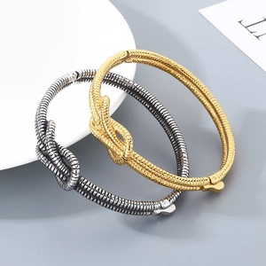 Minimalist knot cuff bracelet in gold and antique silver featuring textured wavy patterns