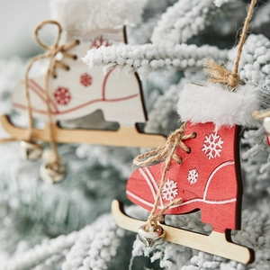 Wooden ice skate Christmas ornaments with bells and snow-covered pine background