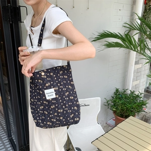 Detail view of vintage floral canvas tote bag worn on shoulder in outdoor cafe