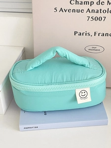 Macro shot of mint green quilted fabric textures and smile logo on portable makeup bag