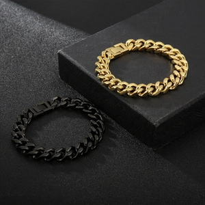 Detailed shot of polished gold and black stainless steel Cuban link bracelets on textured box