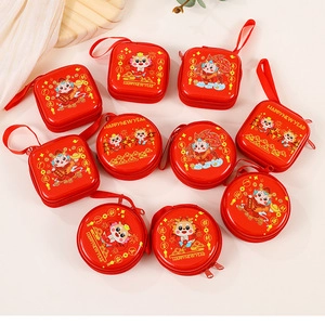 Flat lay of multiple festive red tinplate coin purses with cartoon dragon designs and patterns