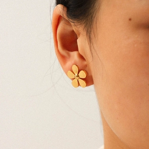 Close-up of golden five-petal flower stud earring on model made of 18k gold plated steel