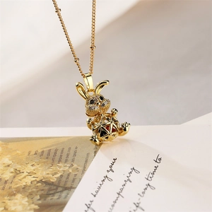 Close-up of golden rabbit pendant with black gemstone eyes and hollow sphere body