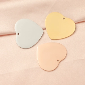 Detailed view of 33mm heart pendants in silver, gold, and rose gold on pink silk