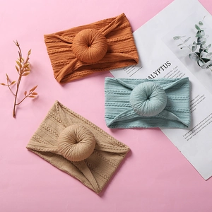 Three soft nylon baby headbands with donut knots in orange, green, and beige colors