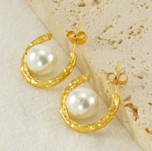 Detailed view of C-shaped hammered gold earrings with elegant white pearls