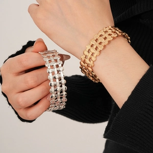 Detailed close-up of wide multi-layer hollow oval metal bracelet in gold and silver