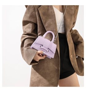 Close-up of lilac pebbled leather mini bag with silver bead chain and top handle on model