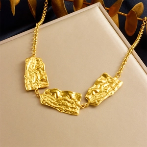 Close-up of golden geometric pendant necklace with irregular hammered metal texture details