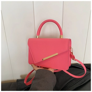 Detail of lychee pattern faux leather on bright pink handbag with golden hardware