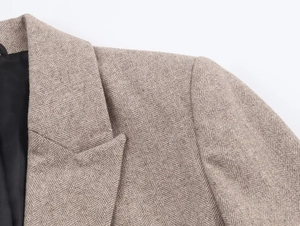Detailed close-up showing the premium herringbone texture and collar of this brown blazer