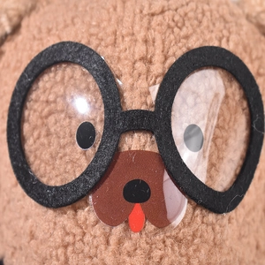 Close-up of cute plush puppy face with black glasses and faux fur baseball cap detail