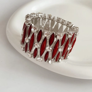 Dettaglio del bracciale vintage in argento con pietre rosse su piatto ceramica