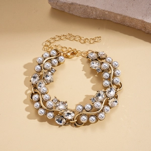 Détail d'un collier vintage doré avec perles d'imitation et cristaux sur fond de sable fin