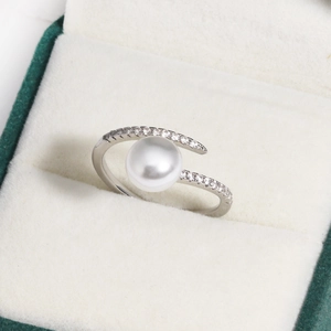 Close-up of adjustable silver ring with large white pearl and zircon accents in a box