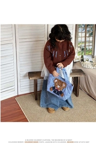 Detail of blue quilted children's bag featuring a 3D plush teddy bear in school uniform