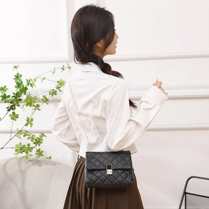 Classic black quilted crossbody bag with gold chain strap shown on a female model