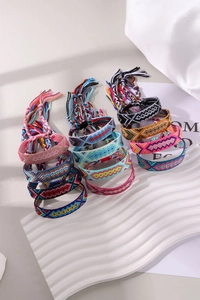 Detail of colorful woven friendship bracelets with tassels on white textured background